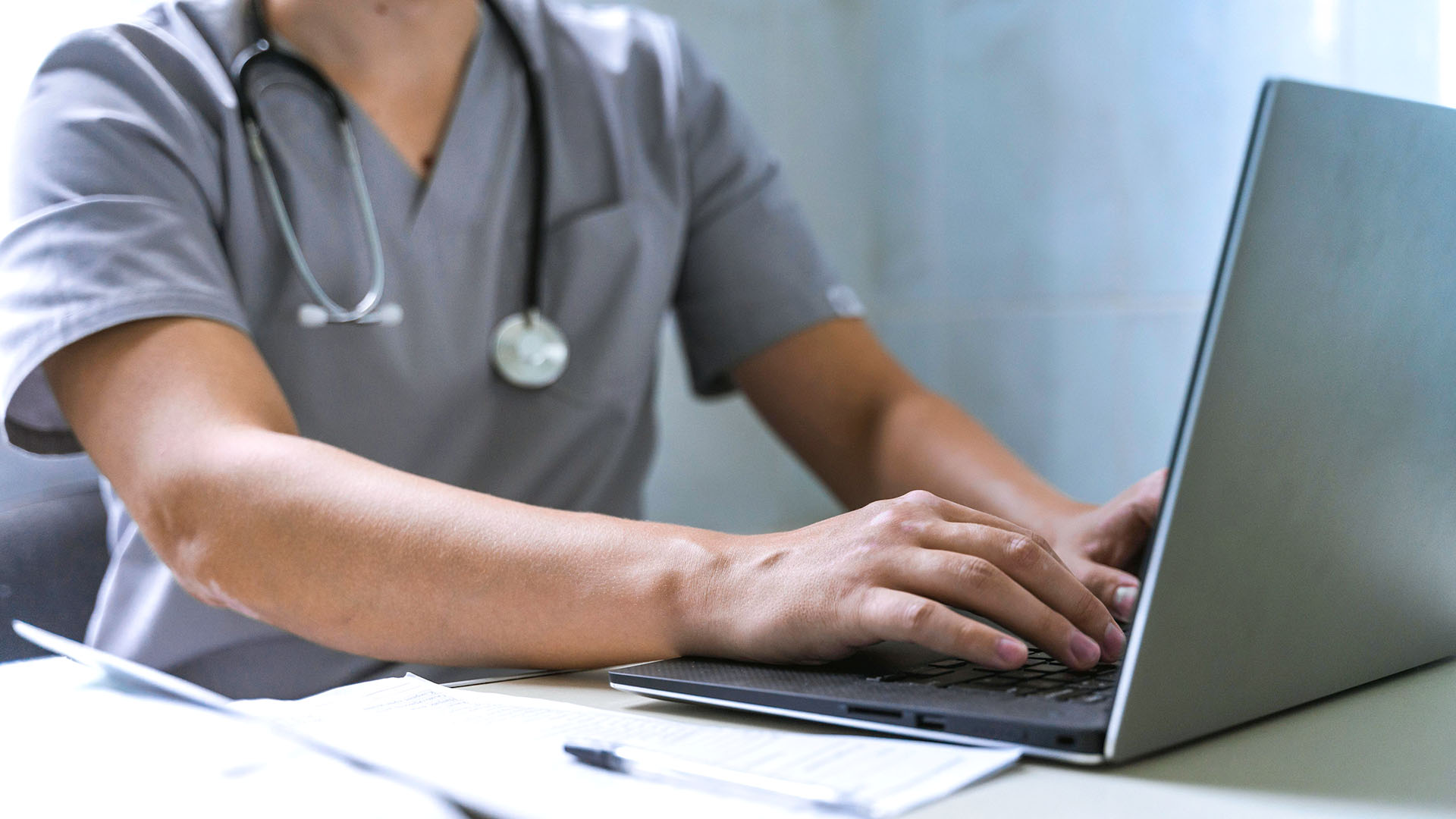 Doctor with stethoscope working on laptop