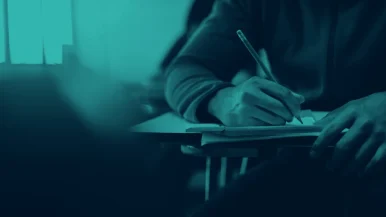 d7ea35147fe93c2855557081c9b3faa5 Student sitting at a desk writing