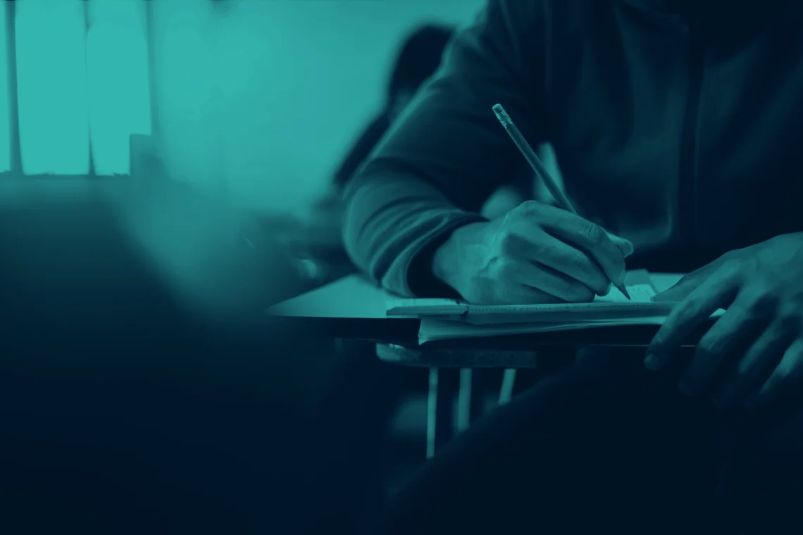 d7ea35147fe93c2855557081c9b3faa5 Student sitting at a desk writing